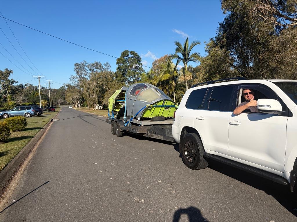 F-111 crew module on trailer arriving in Brisbane, palm trees visible