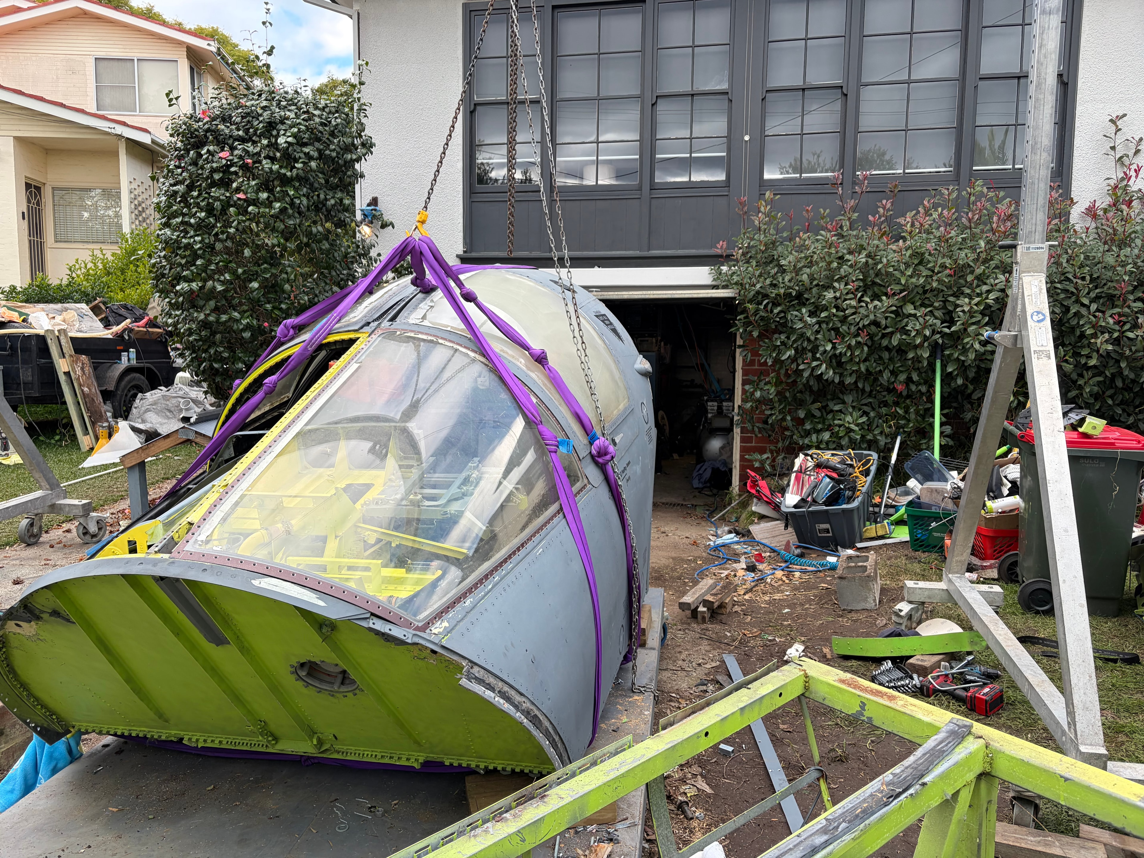 F-111 crew module suspended on chains with purple lifting straps, Sydney